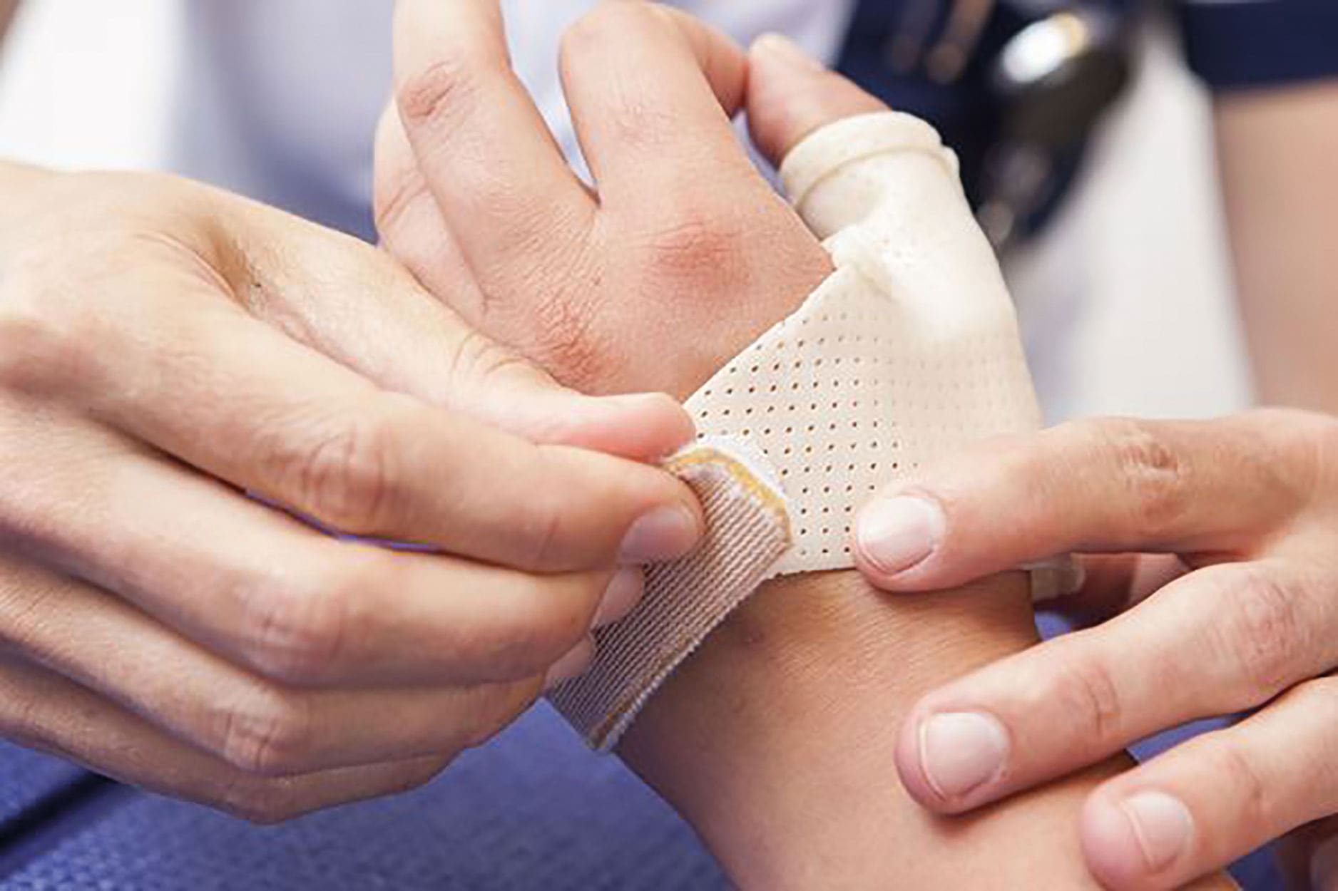 Therapeut legt een tapeverband aan op de hand en pols van een cliënt.
