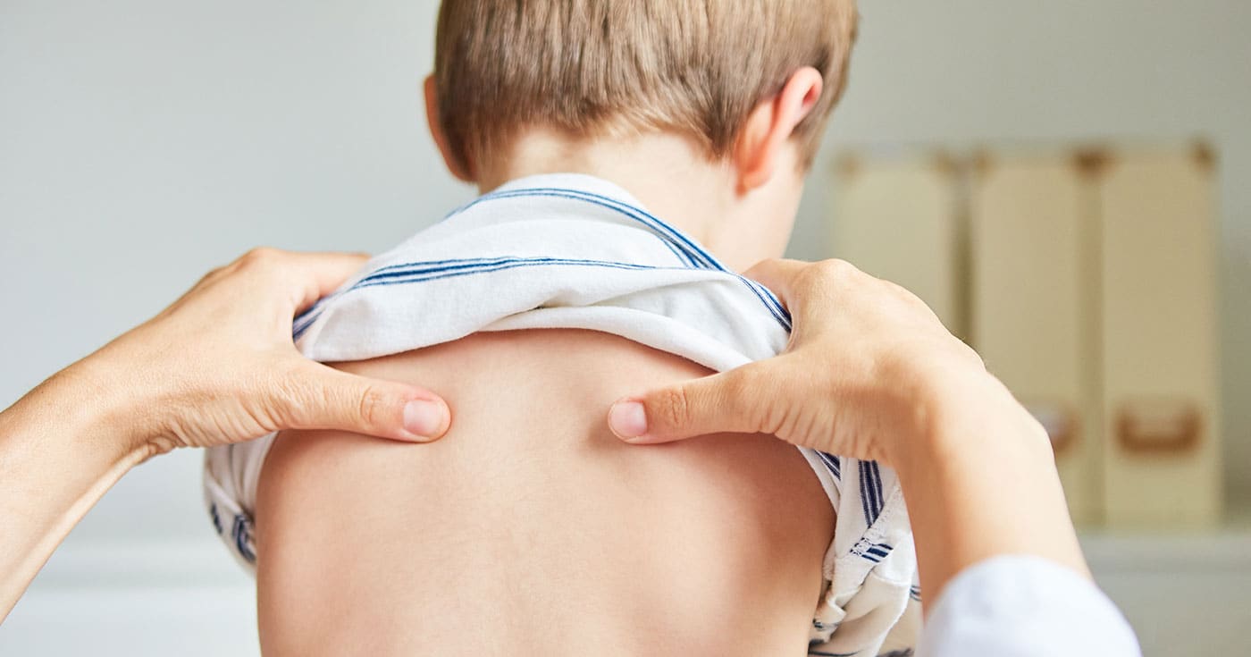 Kinderfysiotherapeut onderzoekt de rug en schouders van een jong kind.
